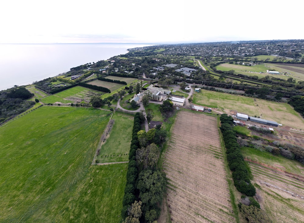 an aerial view of a farm land with a large body of water in the background