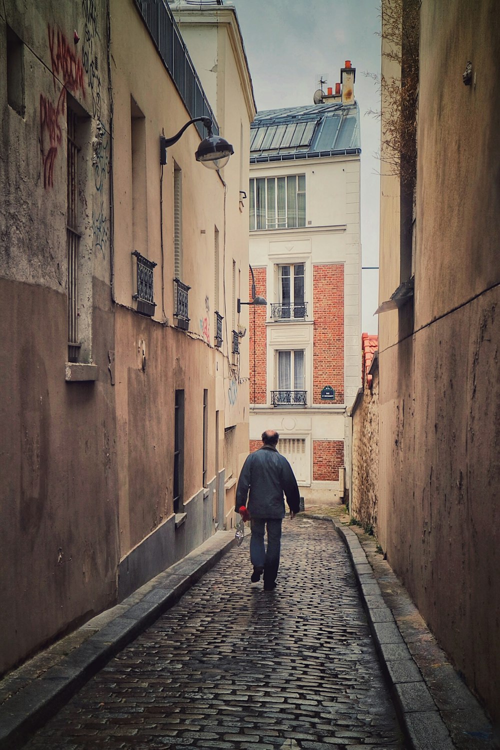 a man is walking down a cobblestone street