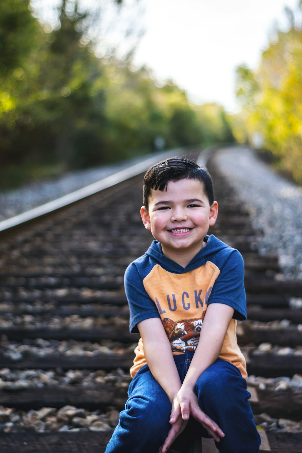 a young boy sitting on top of a train track