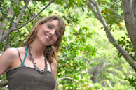 Lifestyle shot of a smiling woman wearing casual chic jewelry while walking near desert plants.