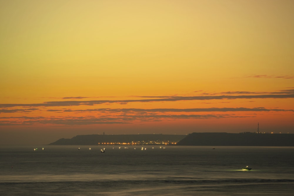 Ein Sonnenuntergang mit Blick auf ein Gewässer mit einer Stadt in der Ferne