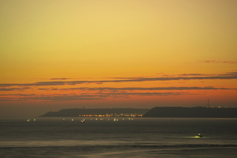 a sunset view of a body of water with a city in the distance