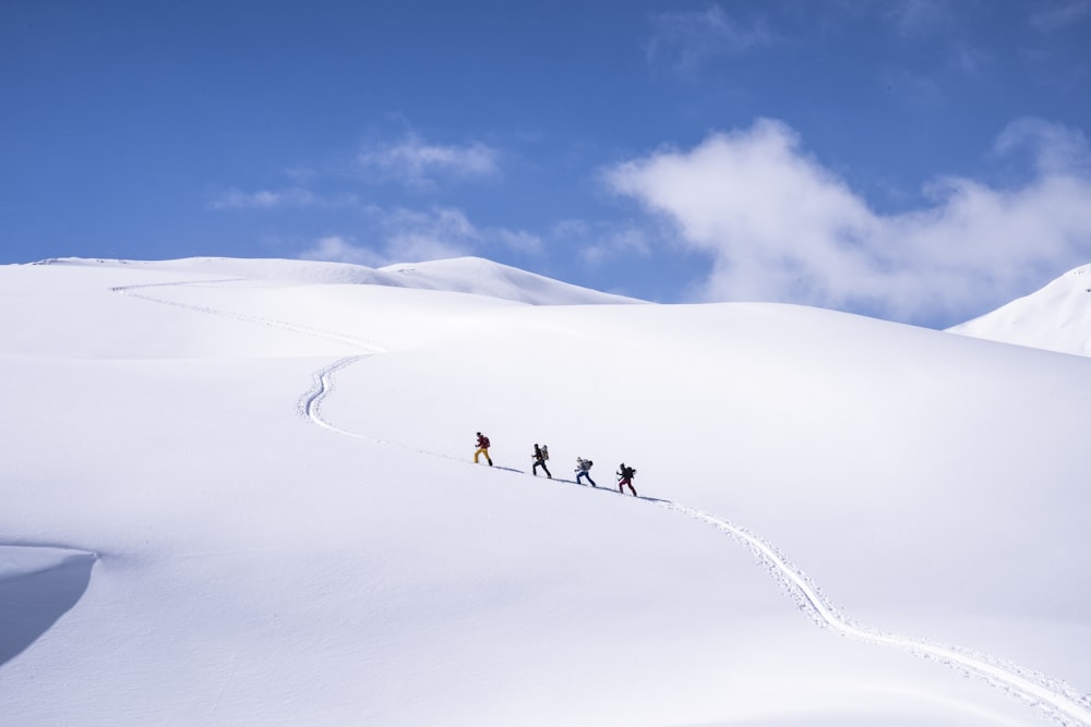 Un gruppo di persone che cavalcano gli sci lungo un pendio innevato