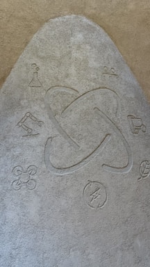 A textured surface features a central atom symbol surrounded by various scientific and technological icons, including a beaker, robotic arm, drone, recycling symbol, and a leaf.