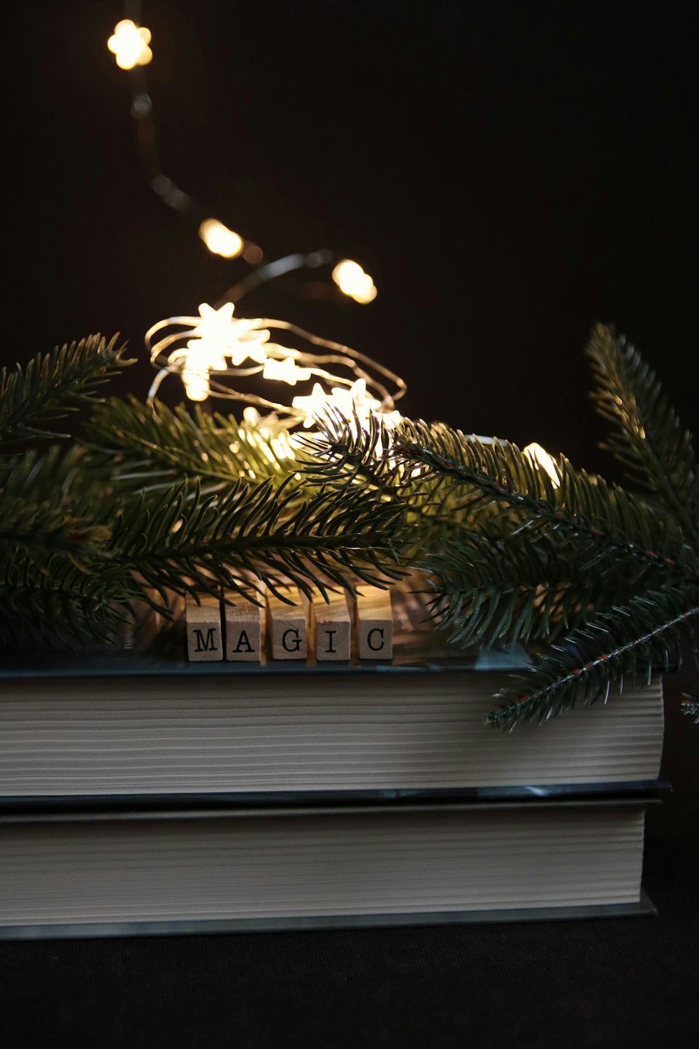 a stack of books with christmas lights on top of them