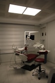 a dentist chair with a red seat in a room