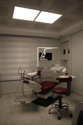 a dentist chair with a red seat in a room