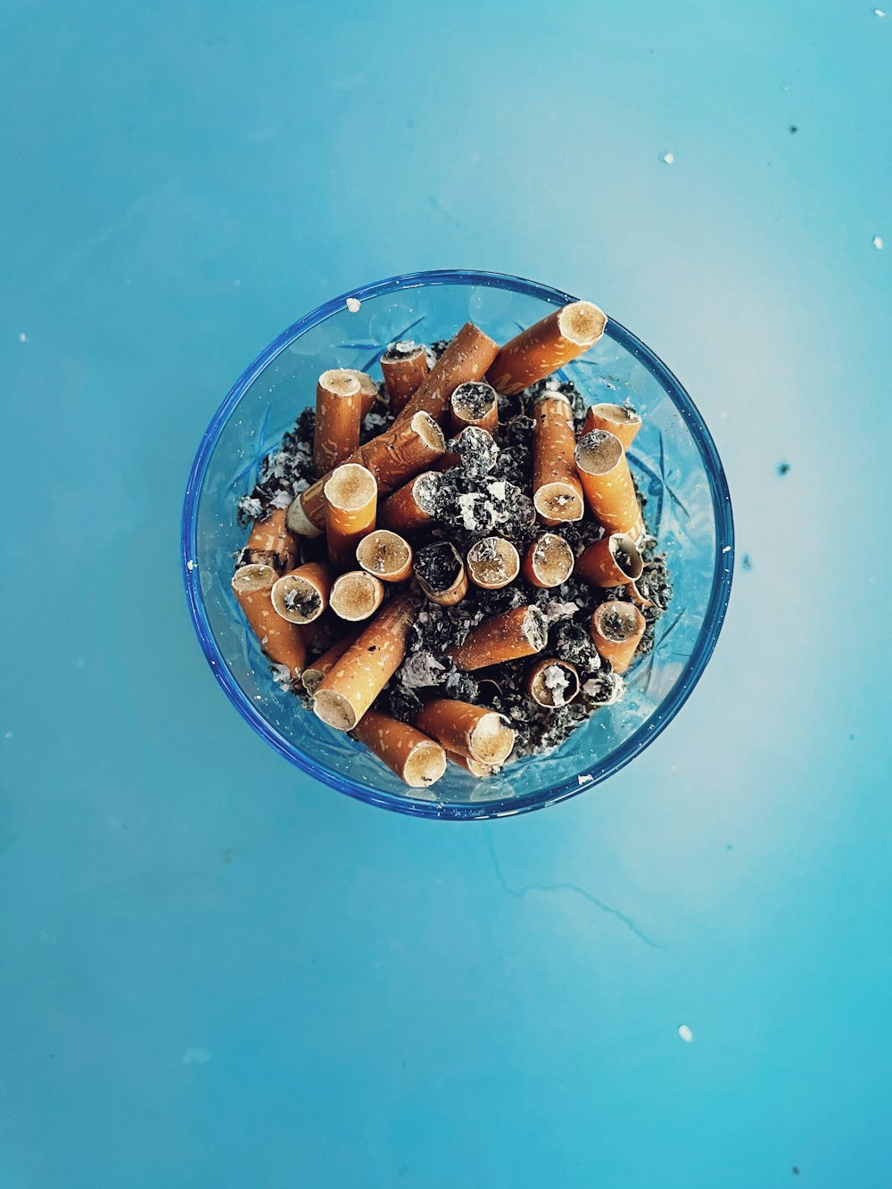 un bol en verre rempli de beaucoup de cigarettes