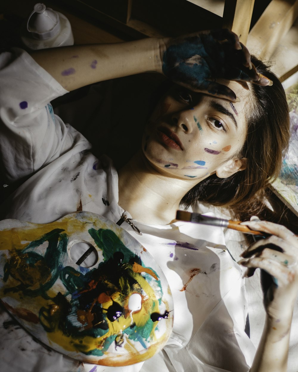 a woman with paint on her face holding a paintbrush