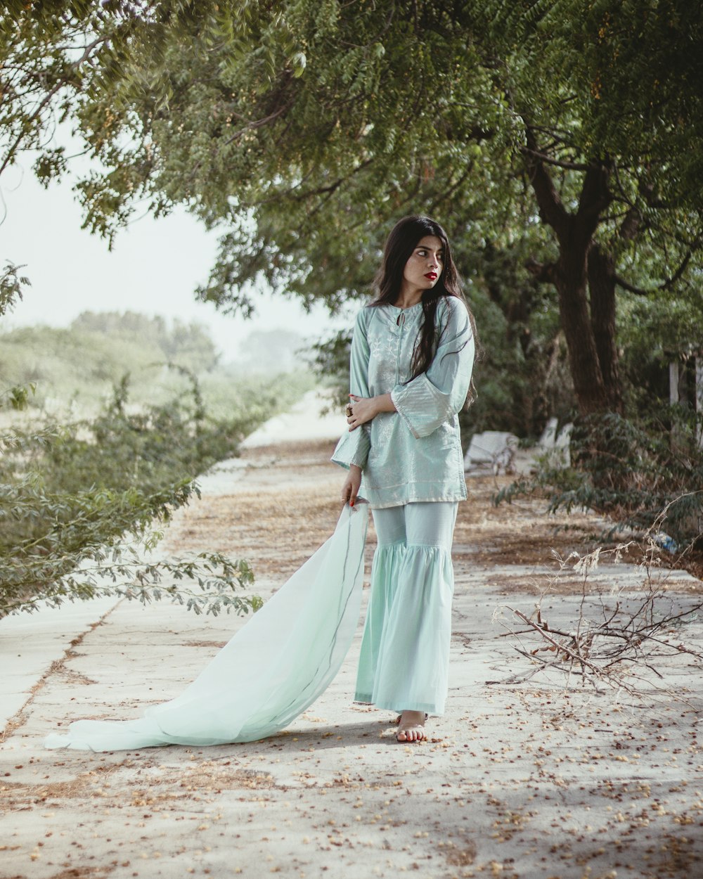 a woman in a blue dress standing on a path