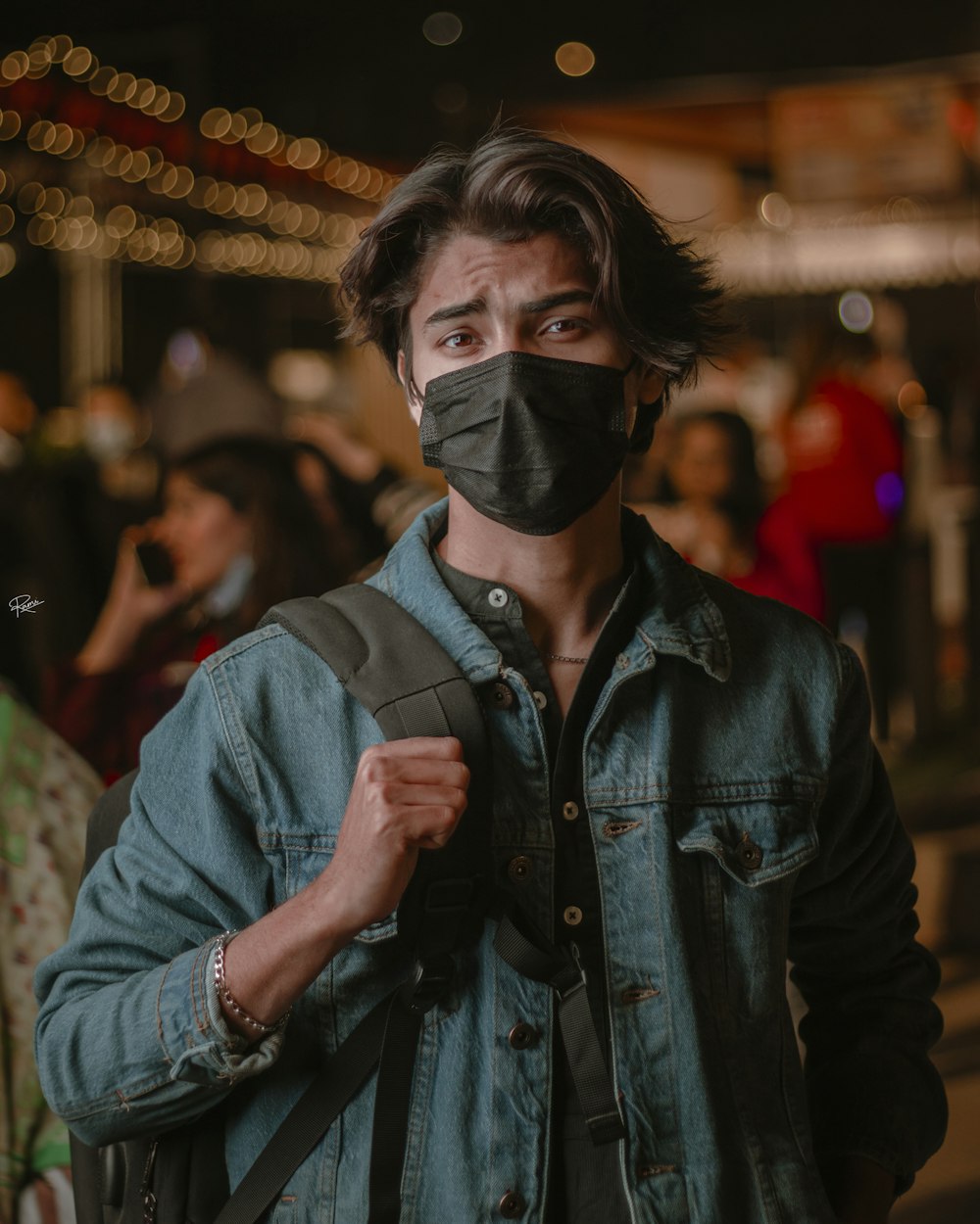 a man wearing a black face mask and a denim jacket