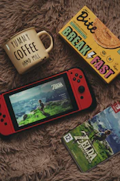 A cozy desk setup featuring a Game Boy Advance SP, retro game cartridges, and a warm cup of coffee.