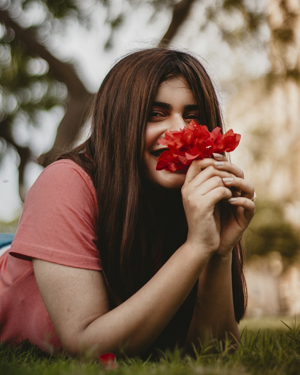 a woman laying on the grass holding a flower