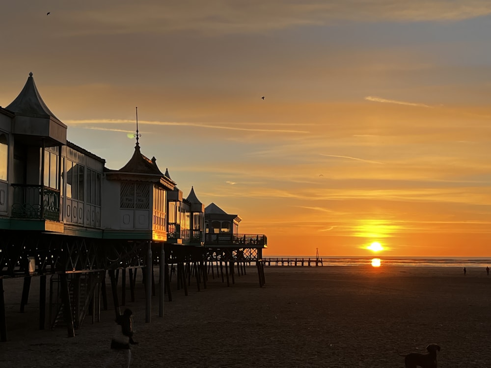 a sunset view of a beach with a pier
