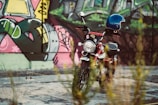 A close-up of a motorcycle with vibrant city graffiti in the background.