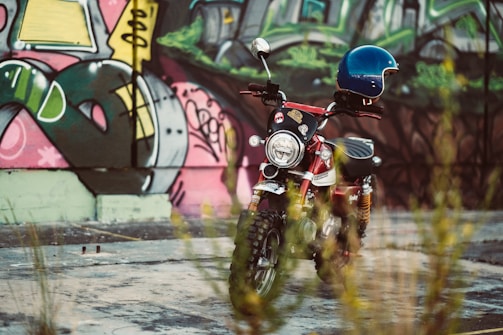 A close-up of a motorcycle with vibrant city graffiti in the background.