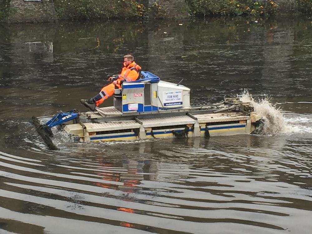 a man in an orange vest is on a small boat