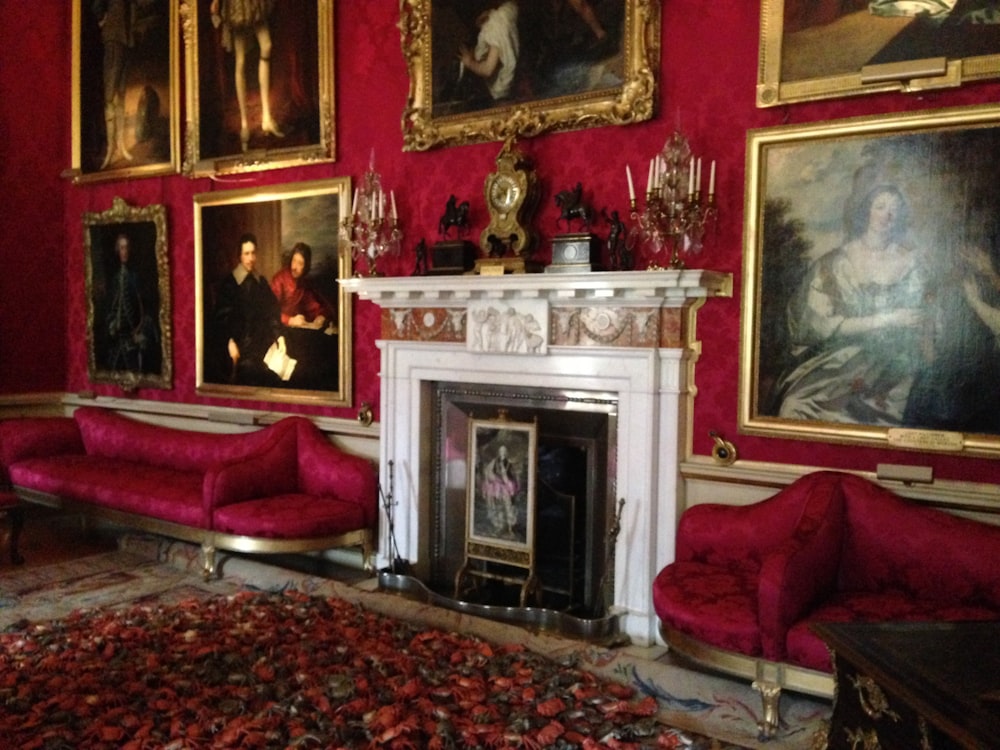 a living room with red walls and paintings on the wall