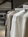 An elegant, minimalist wardrobe featuring neutral-toned Elio Fraga garments hanging neatly.