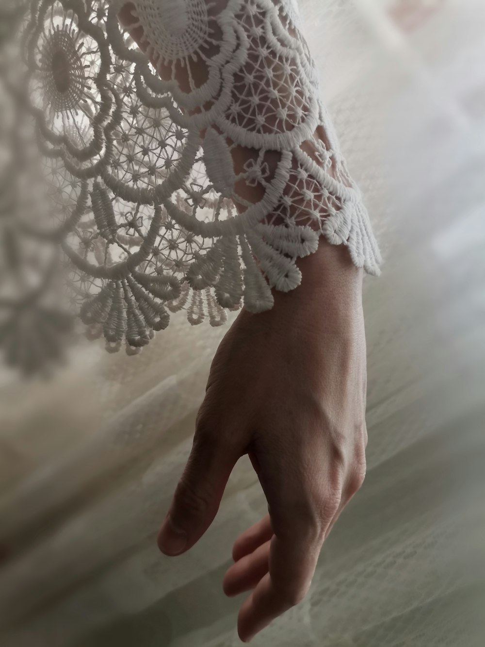 a person's hand is holding a lace doily