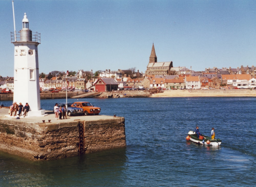 a group of people in a small boat near a light house