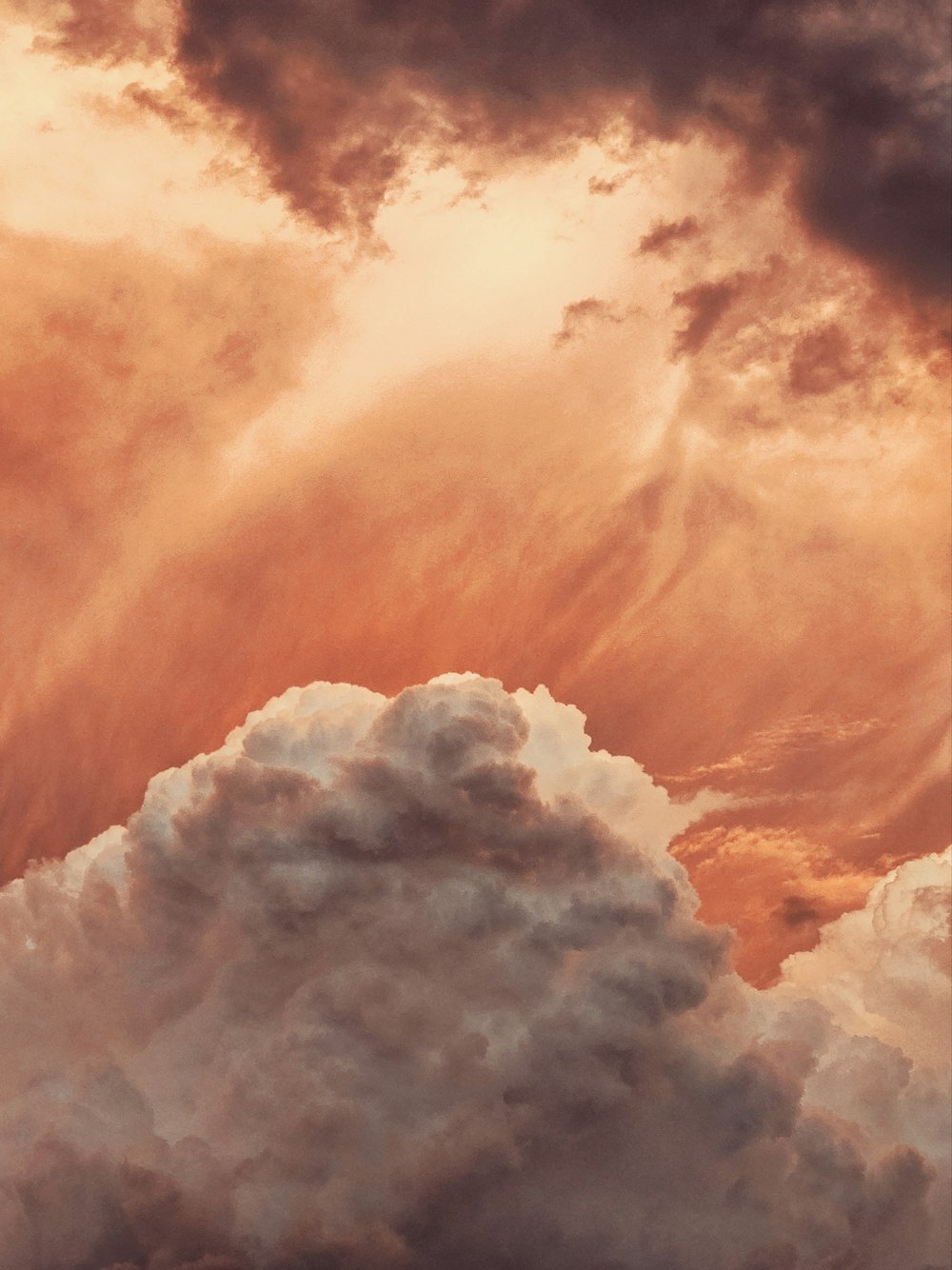 a plane flying through a cloudy sky at sunset