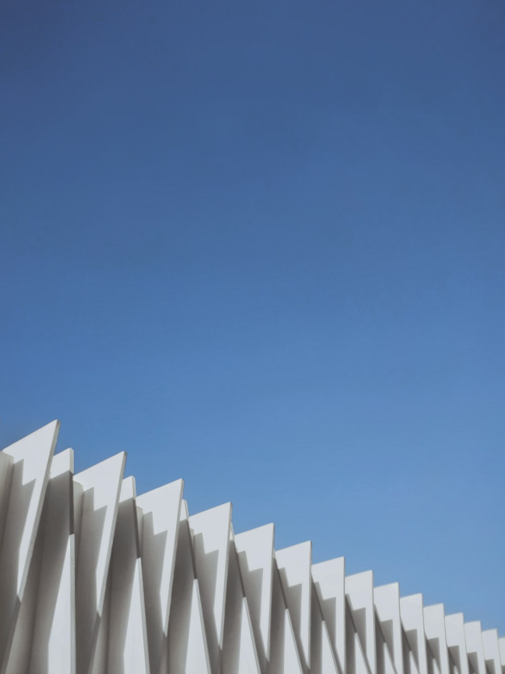 a plane flying over a white building with a blue sky in the background