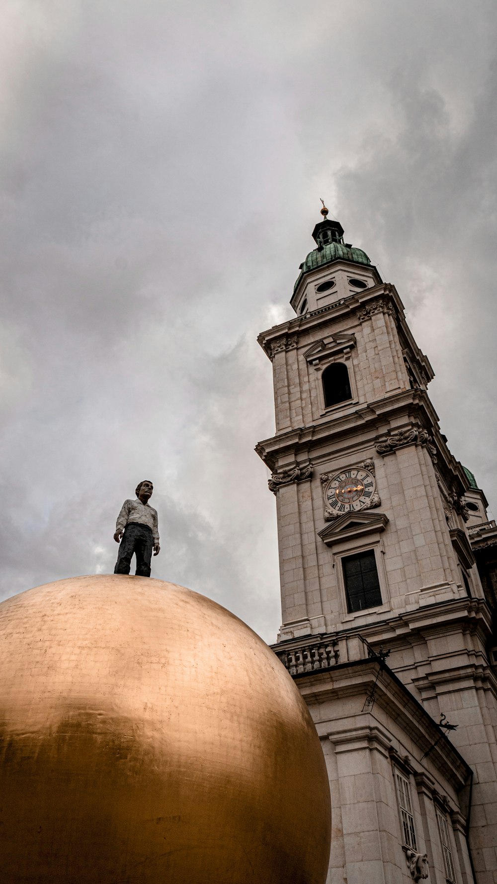 a man standing on top of a golden ball in front of a building