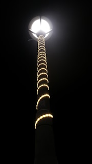 Street lighting poles with bright, energy-efficient lamps lighting up an urban road at night.
