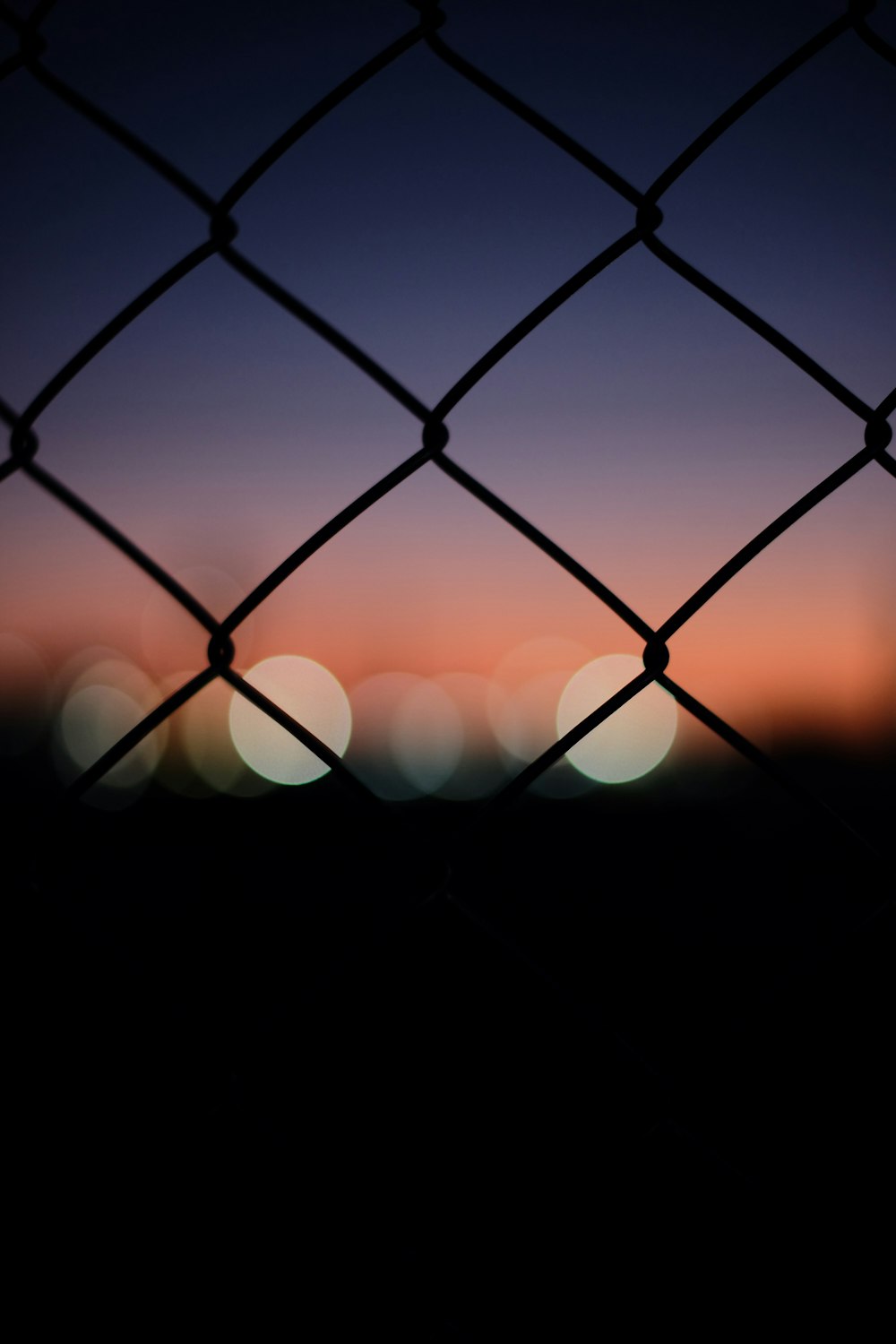 a chain link fence with a sunset in the background