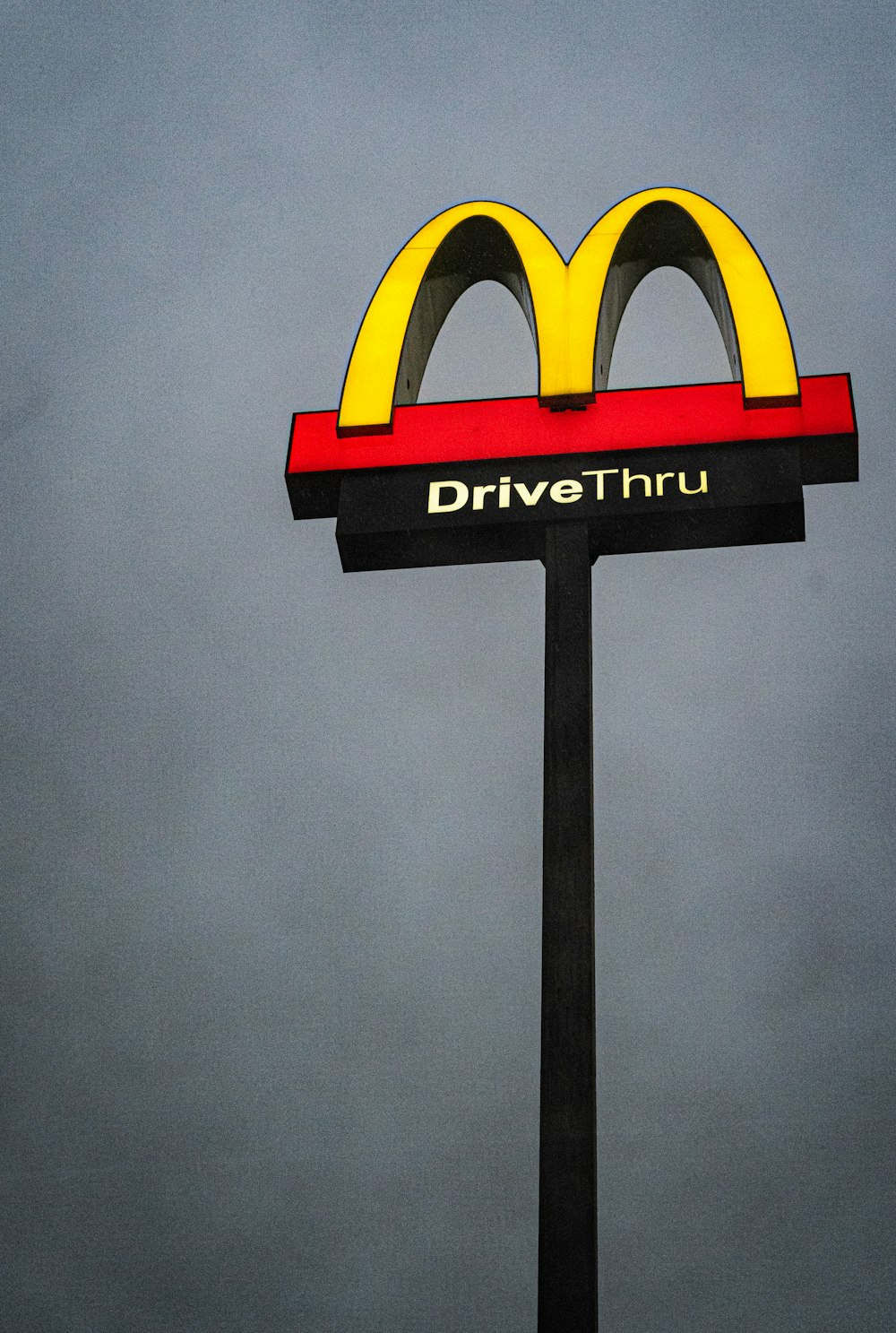 a mcdonald's drive thru sign with a cloudy sky in the background