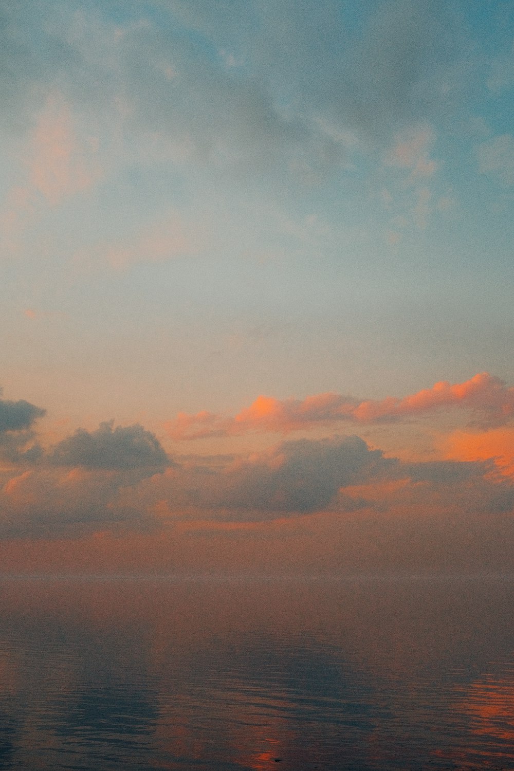 a plane flying over a body of water under a cloudy sky