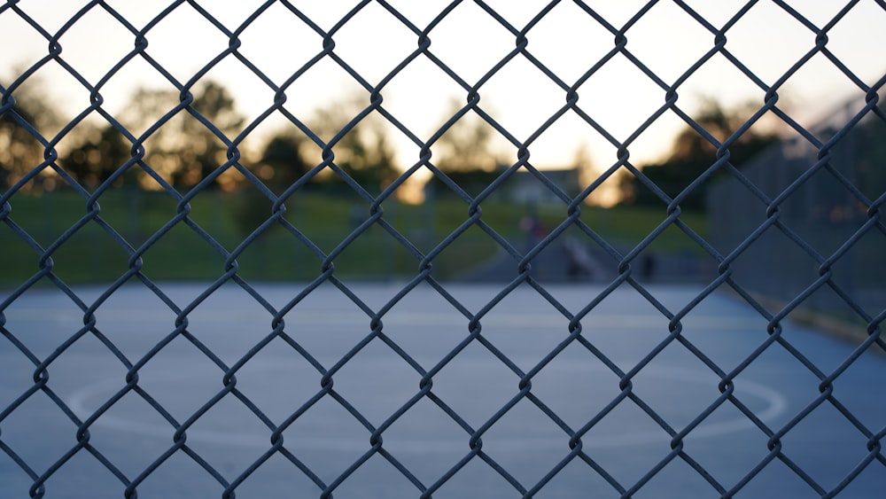 uma quadra de basquete vista através de uma cerca de elo de corrente
