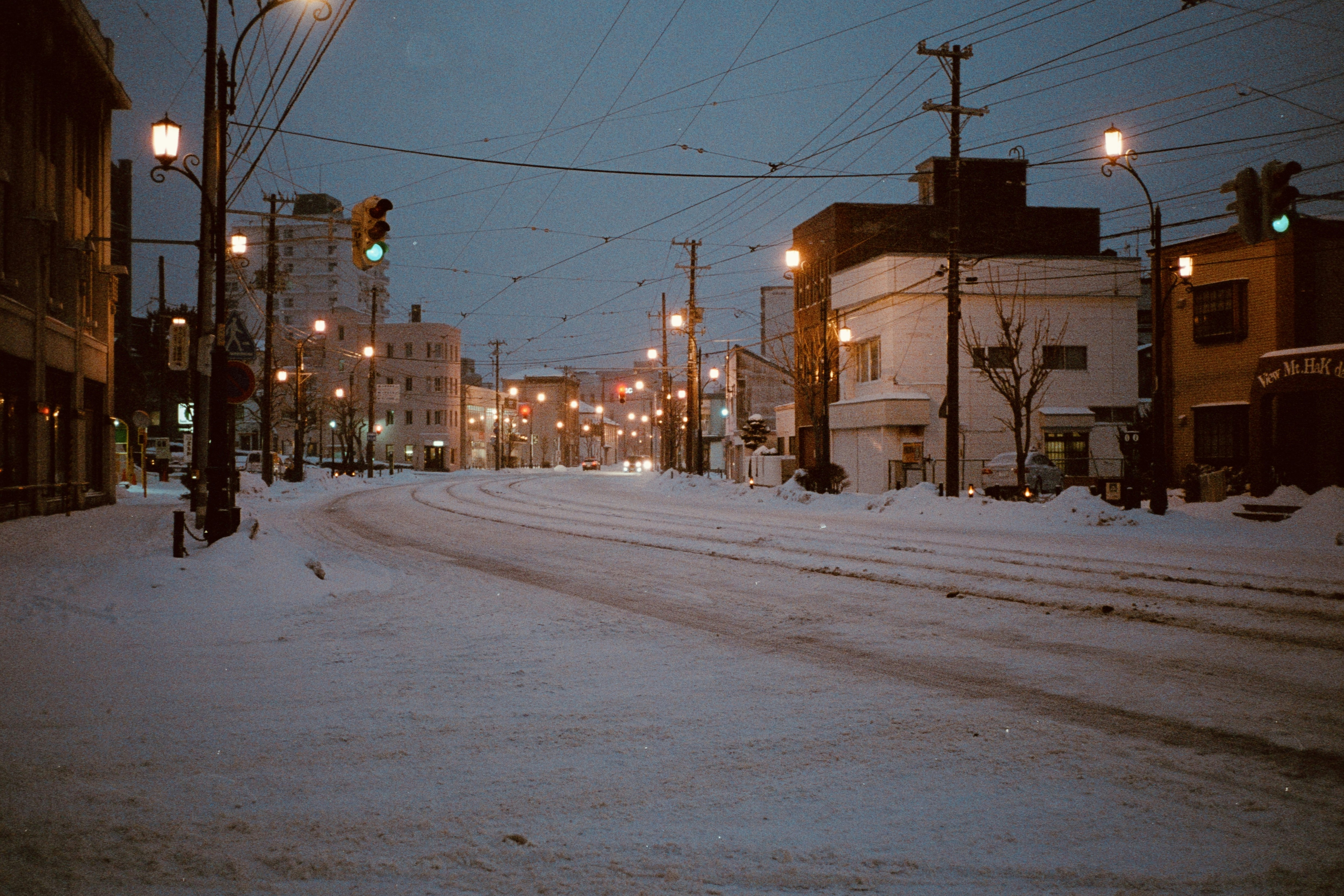 Una calle de la ciudad está cubierta de nieve por la noche