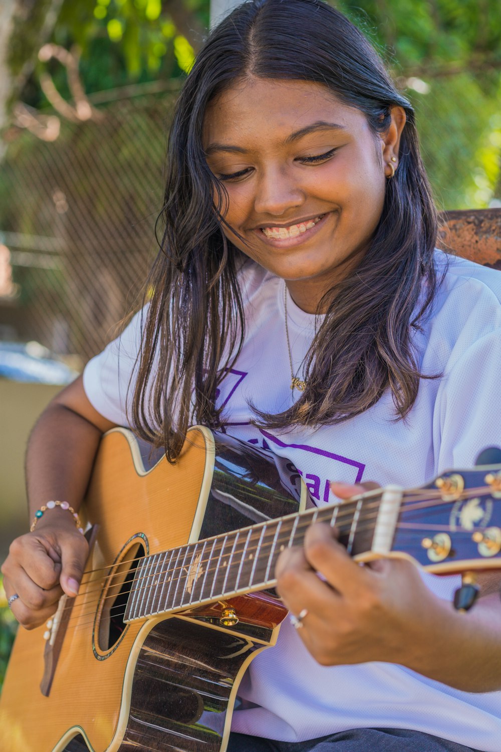a young girl smiles while playing a guitar