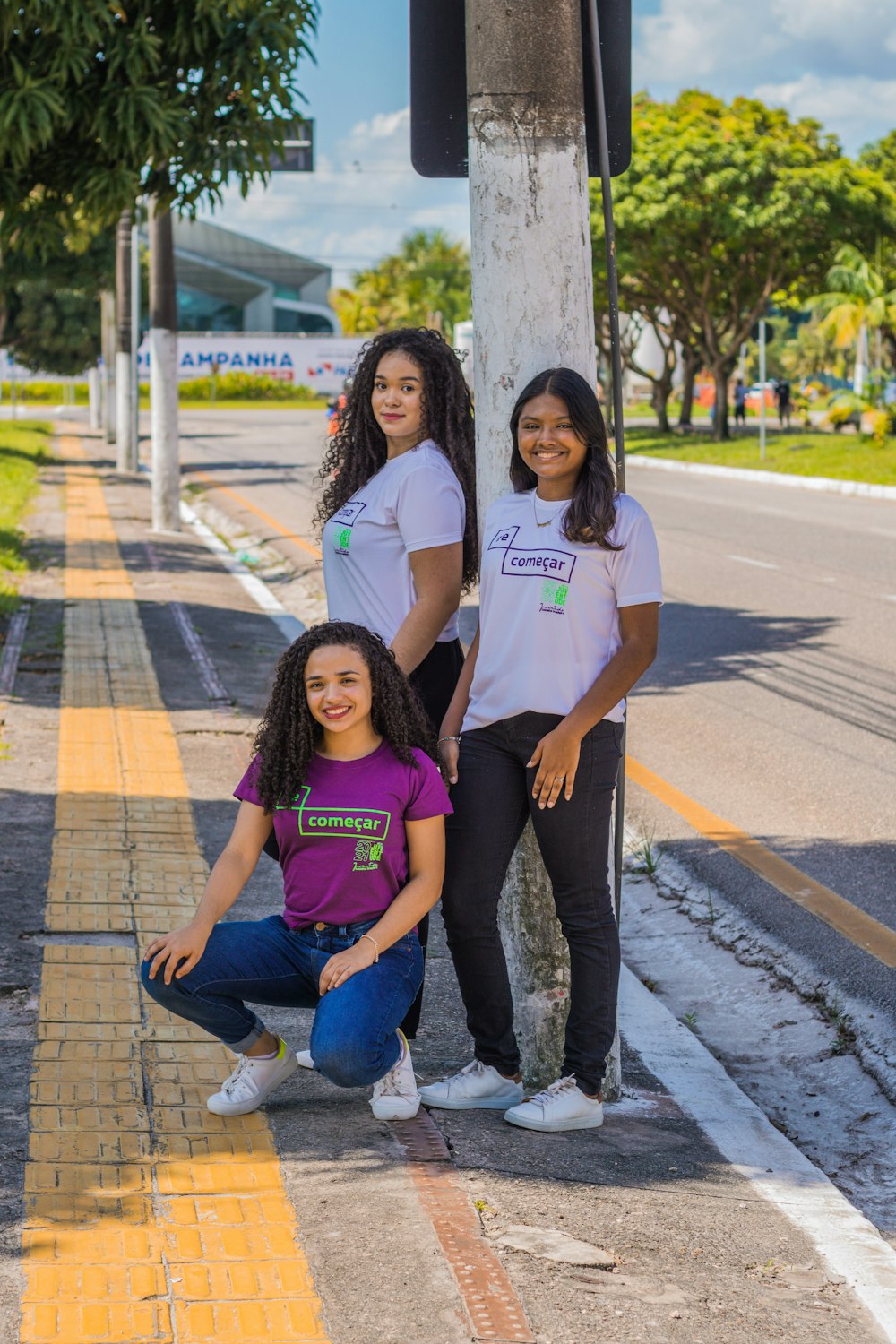 a group of three women standing next to a tree