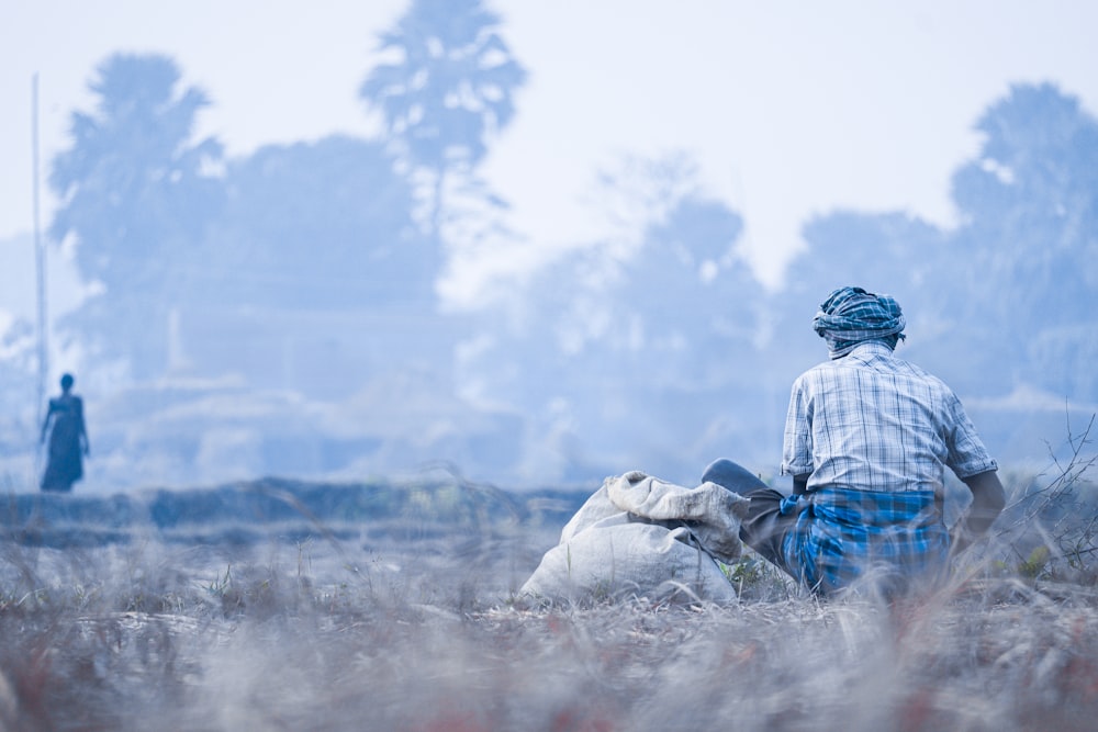 a man sitting in the middle of a field