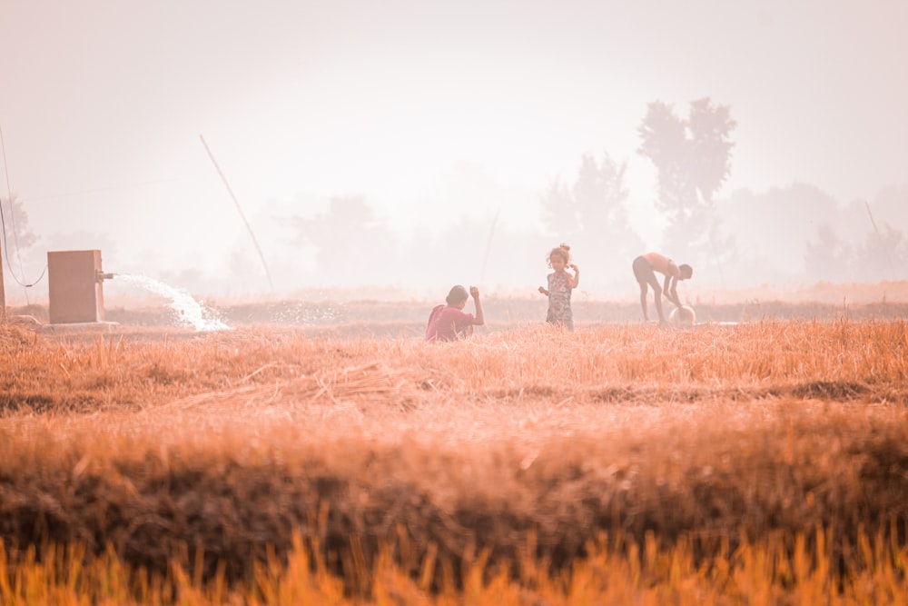 a group of people standing on top of a dry grass field