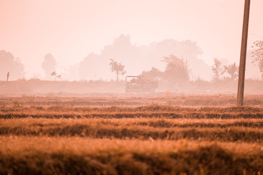 a farm field with a tractor in the distance