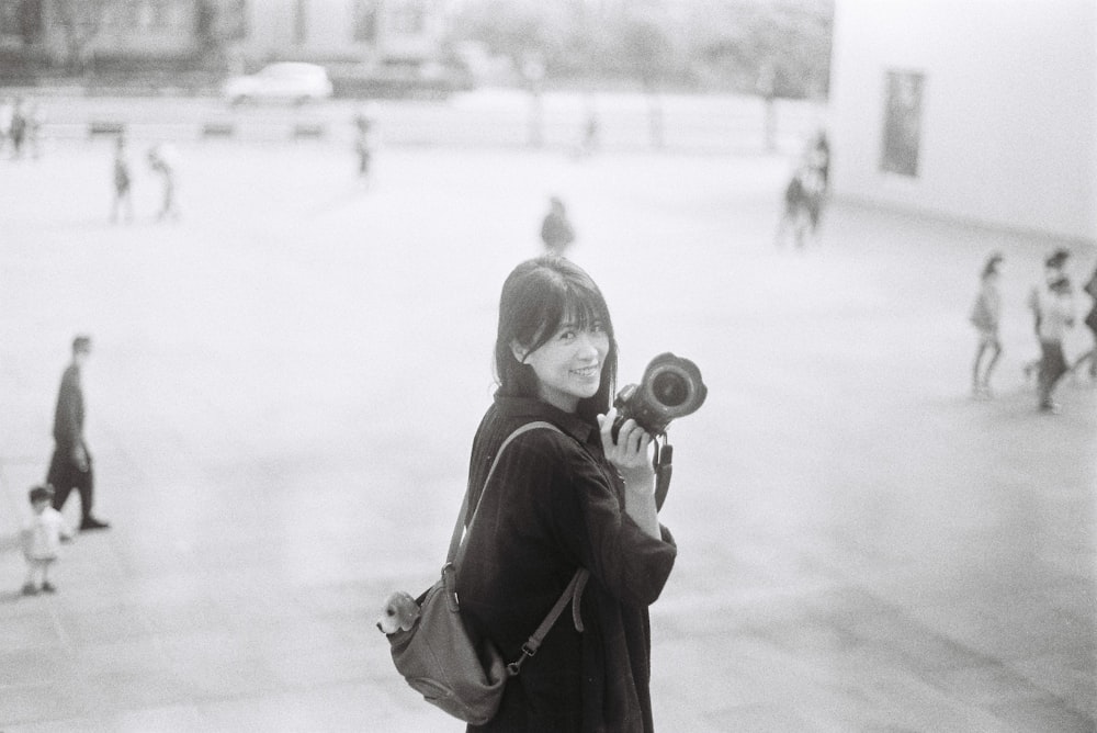 a woman standing in a courtyard holding a camera