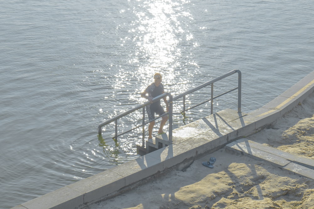 a woman is standing on the steps to the water