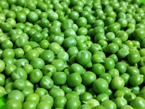 a green bowl filled with peas on top of a table