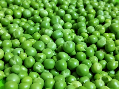 a green bowl filled with peas on top of a table