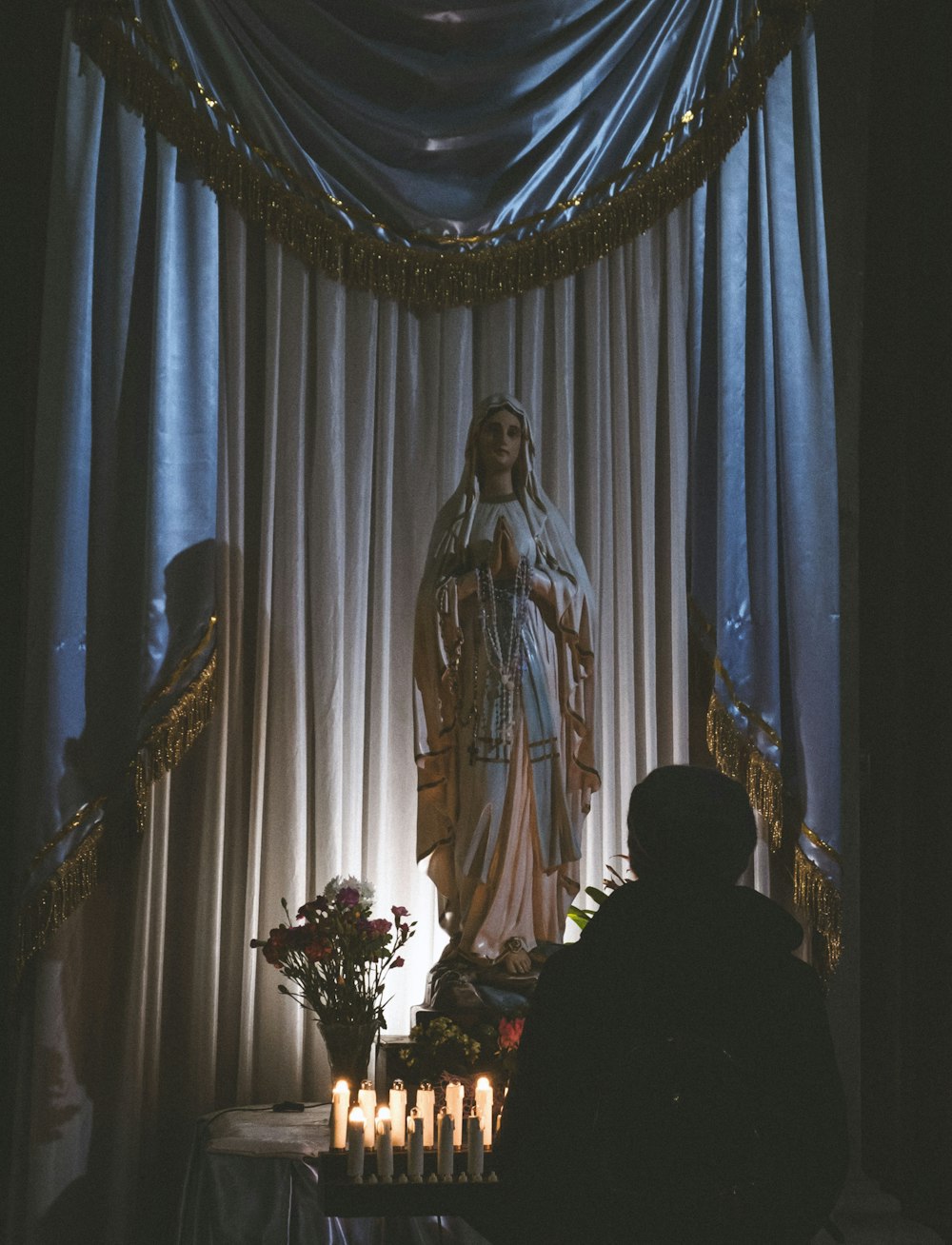 a woman standing in front of a statue with candles