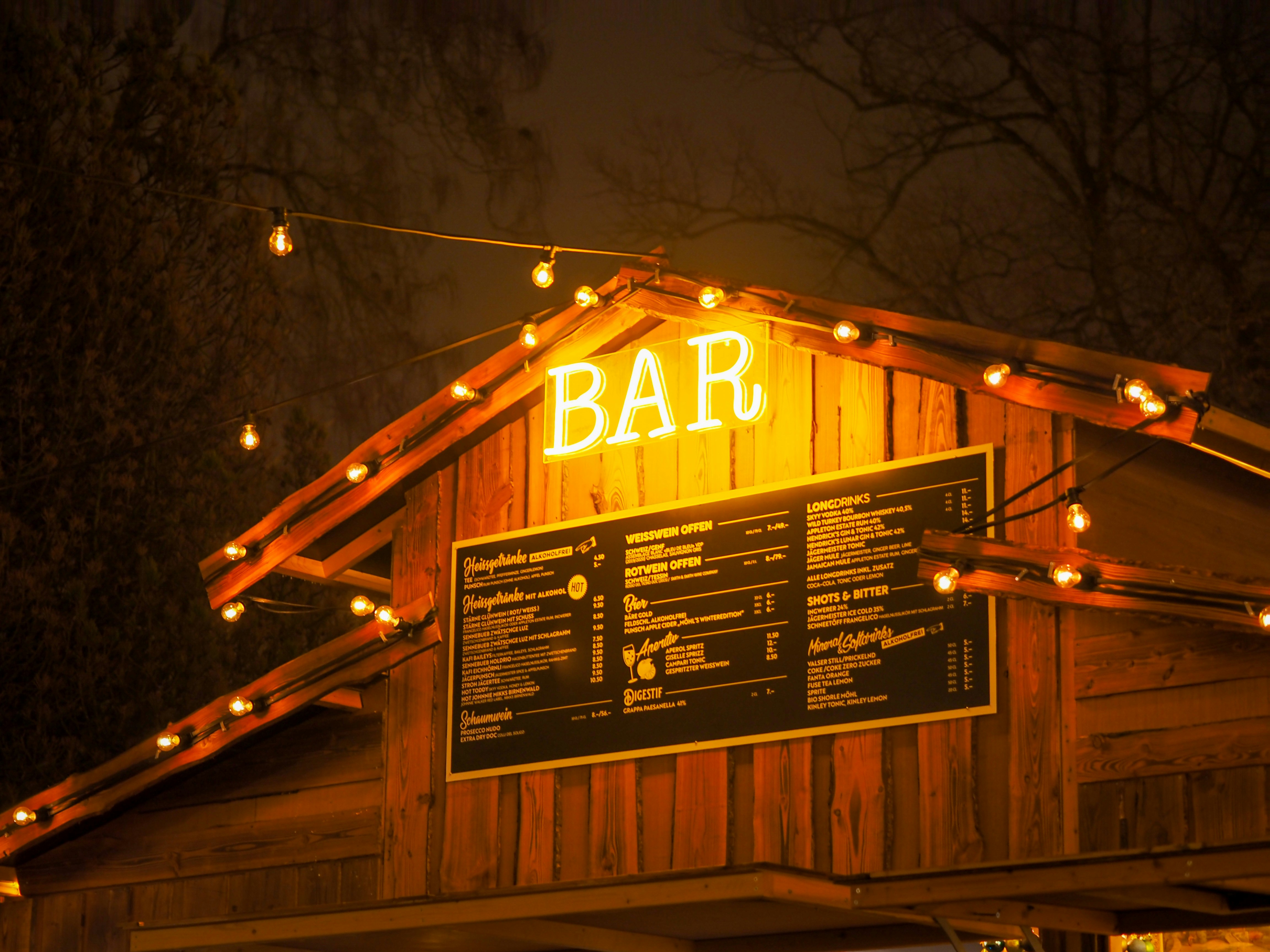 Timber bar building with glowing BAR sign and menu board