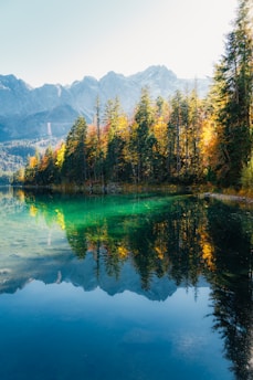 A serene mountain lake reflecting the vibrant colors of an autumn sunset.