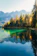 A serene mountain lake reflecting vivid autumn foliage under a soft morning sky.