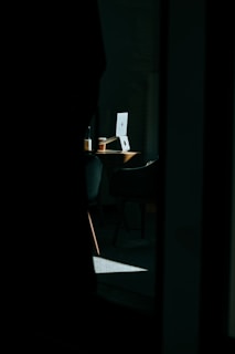 A dimly lit desk with political books, a laptop showing news articles, and a cup of coffee, evoking a thoughtful atmosphere.