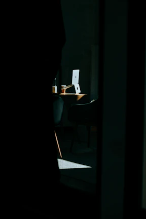 Close-up of a journalist typing on a laptop with a cup of coffee nearby in a dimly lit room.
