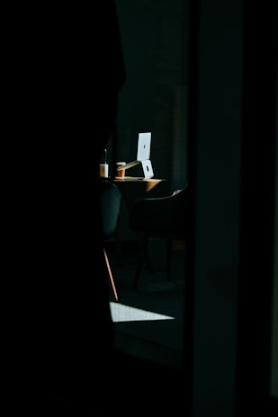 A dimly lit desk with political books, a laptop showing news articles, and a cup of coffee, evoking a thoughtful atmosphere.